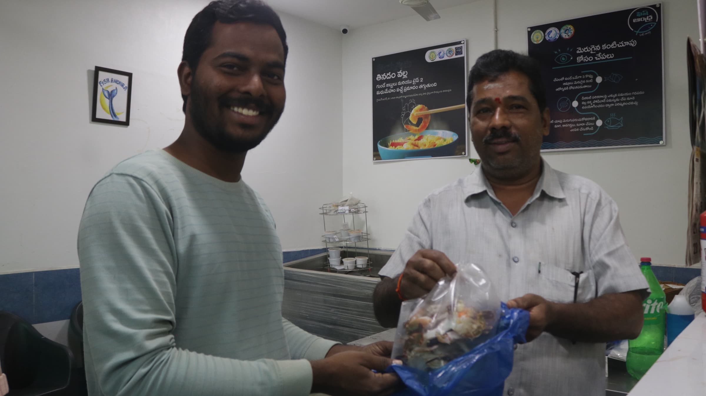 A smiling HasiruAqua team member hands a bag of fresh fish to a customer inside a branded store