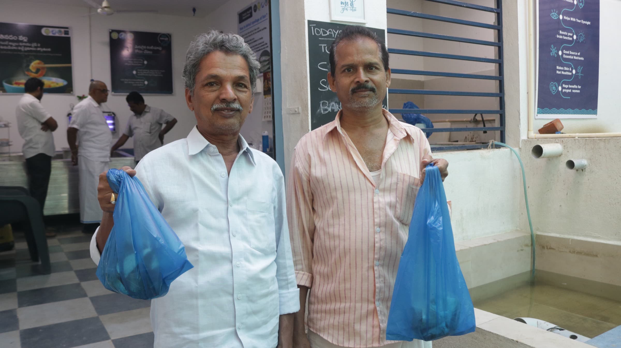 Two customers hold blue bags of fresh fish inside a branded HasiruAqua live-fish store