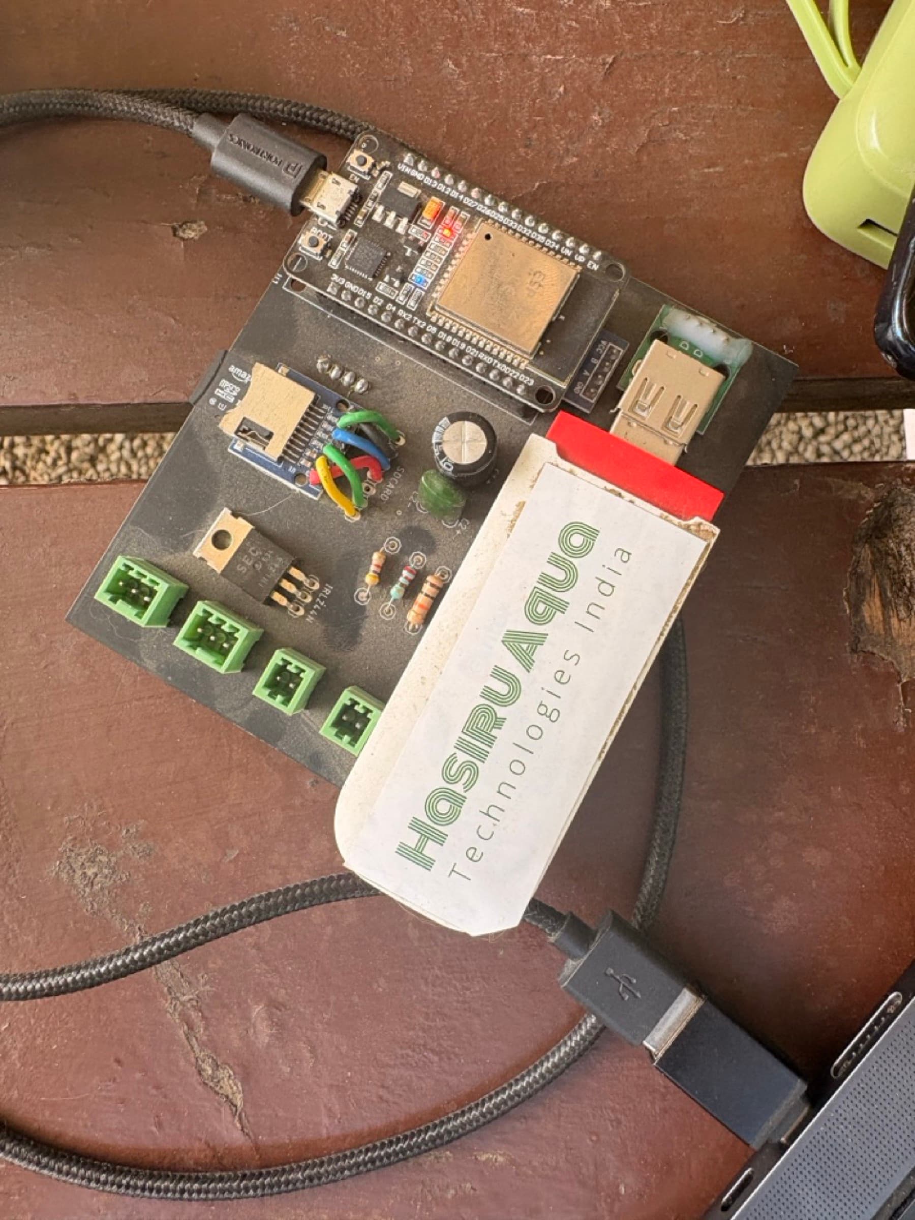 A MeenDoctru sensor board and a HasiruAqua-branded module on the red earth of a farm — the hardware, in the field